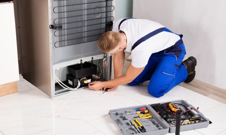 Teknisi SekawanElectro memperbaiki bagian belakang kulkas